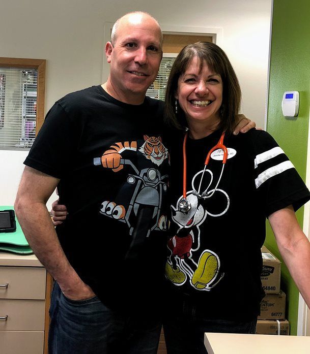 A man and a woman are posing for a picture and the woman is wearing a mickey mouse shirt