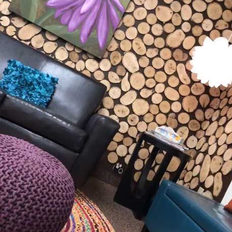 A living room with a couch , ottoman , table and painting on the wall.