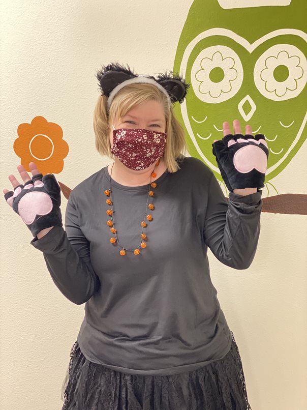 A woman wearing a mask and gloves is standing in front of an owl.