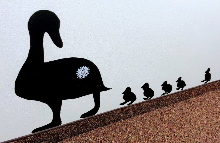A silhouette of a duck and ducklings on a wall