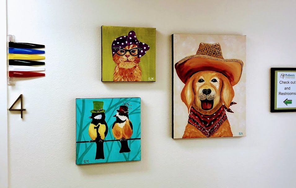 Four paintings on a wall including one of a dog wearing a cowboy hat