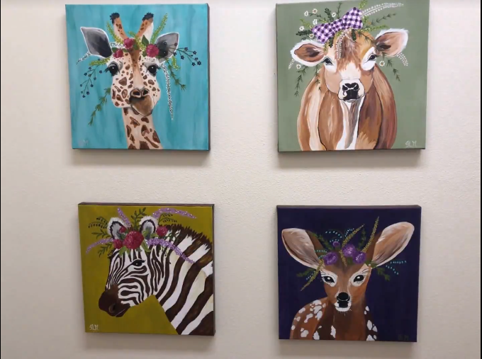 Four paintings of animals on a wall including a giraffe a zebra and a deer