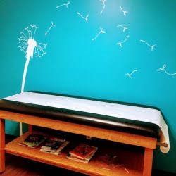 A wooden bench with a dandelion on the wall behind it.