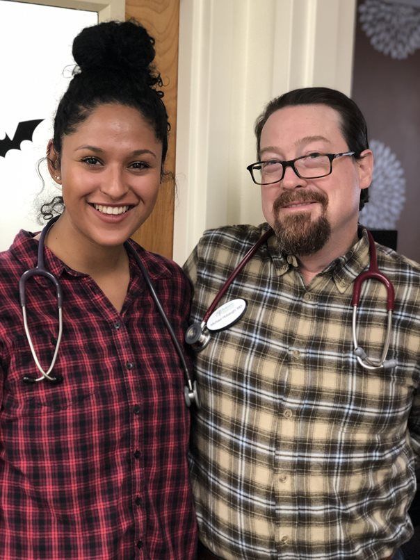 A man and a woman are posing for a picture with stethoscopes around their necks.