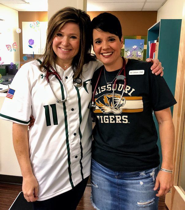 Two women posing for a picture with one wearing a missouri tigers shirt