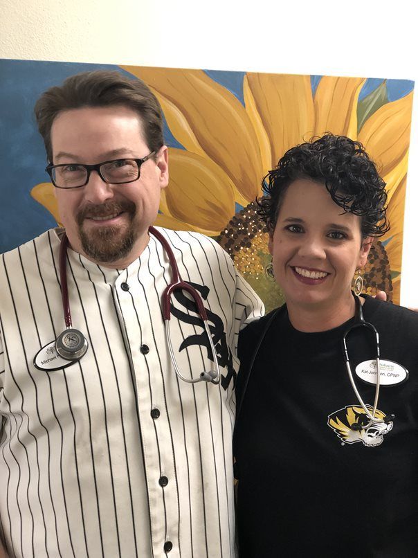 A man and a woman are posing for a picture in front of a sunflower