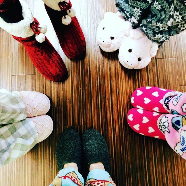 A group of people wearing slippers and socks are standing in a circle