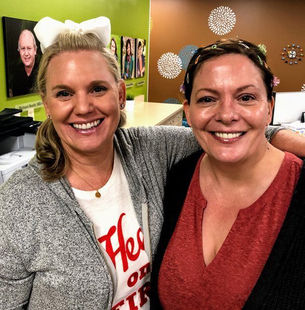 Two women posing for a picture with one wearing a shirt that says her on it