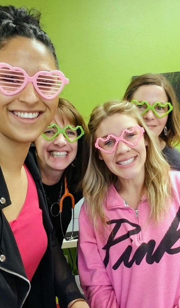 A group of women wearing heart shaped sunglasses are posing for a picture.