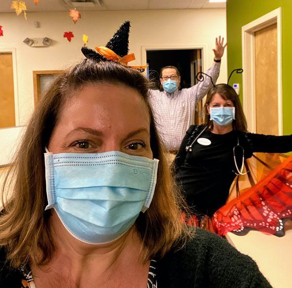 A woman wearing a face mask with a witch hat on her head