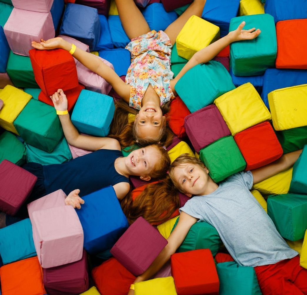 A group of children are standing in a gym watching a man climb a ladder