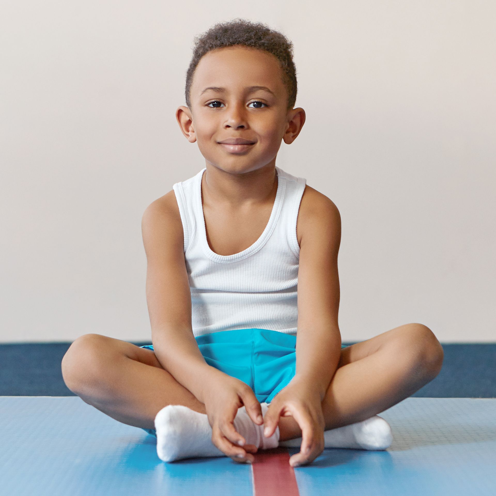 A young boy is sitting on the floor with his legs crossed