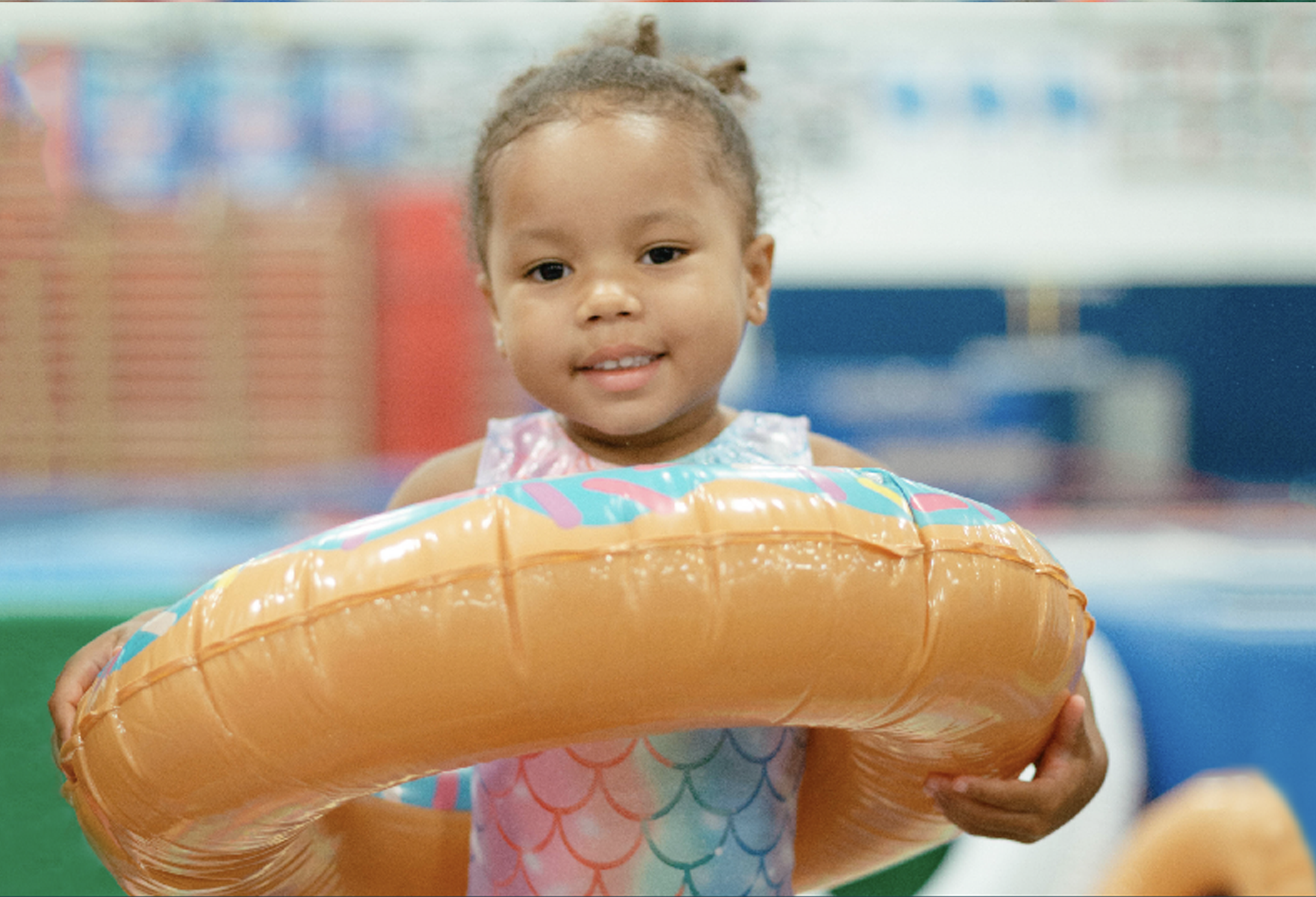 A little girl is holding an inflatable ring in her hands.