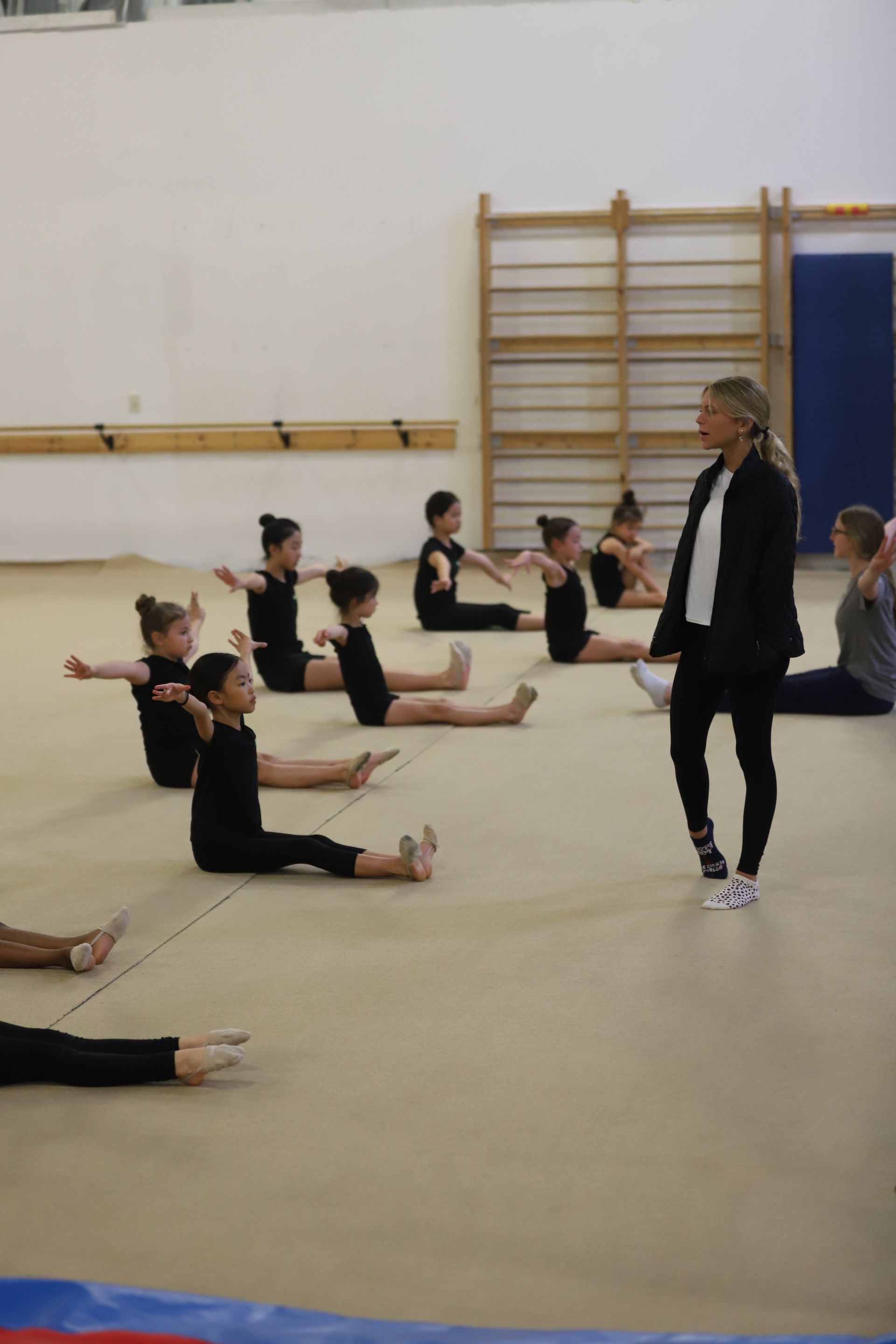 A group of young girls are doing stretching exercises in a gym.