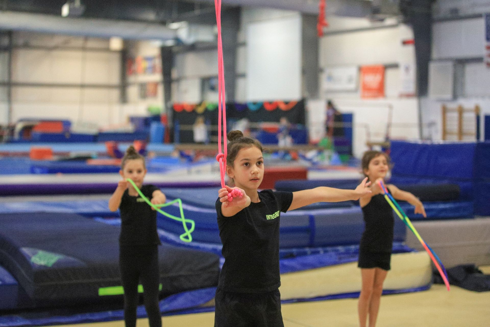 A group of young girls are practicing rhythmic gymnastics in a gym.