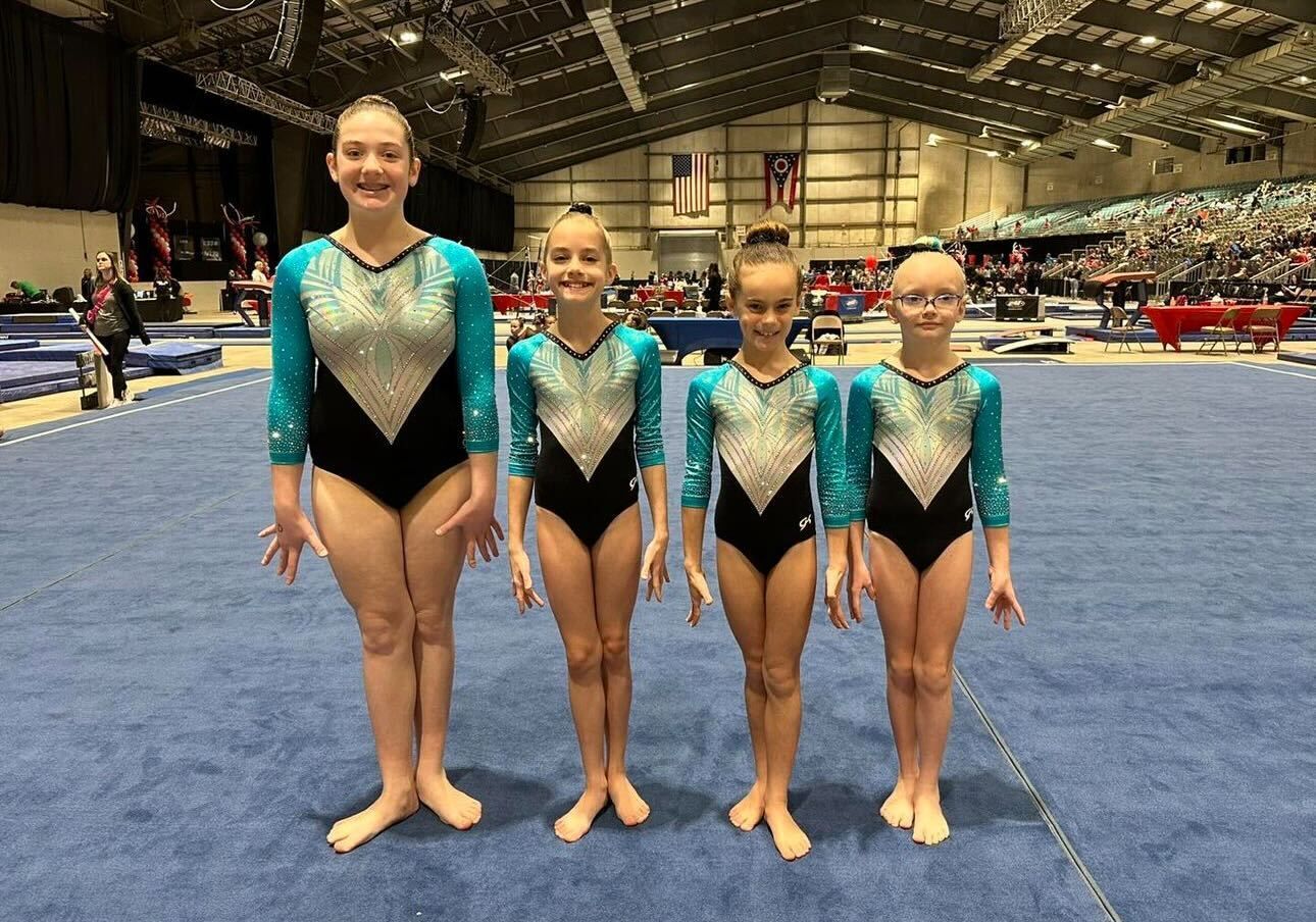 A group of young girls are standing next to each other on a gymnastics floor.