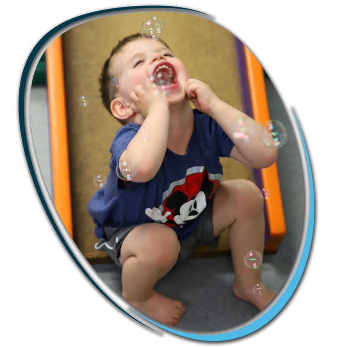 A little boy wearing a mickey mouse shirt is playing with soap bubbles