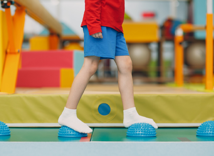 A young boy is standing on a balance beam in a gym.