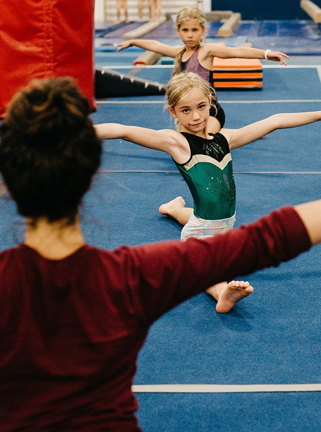 A group of young girls are practicing gymnastics on a blue mat.