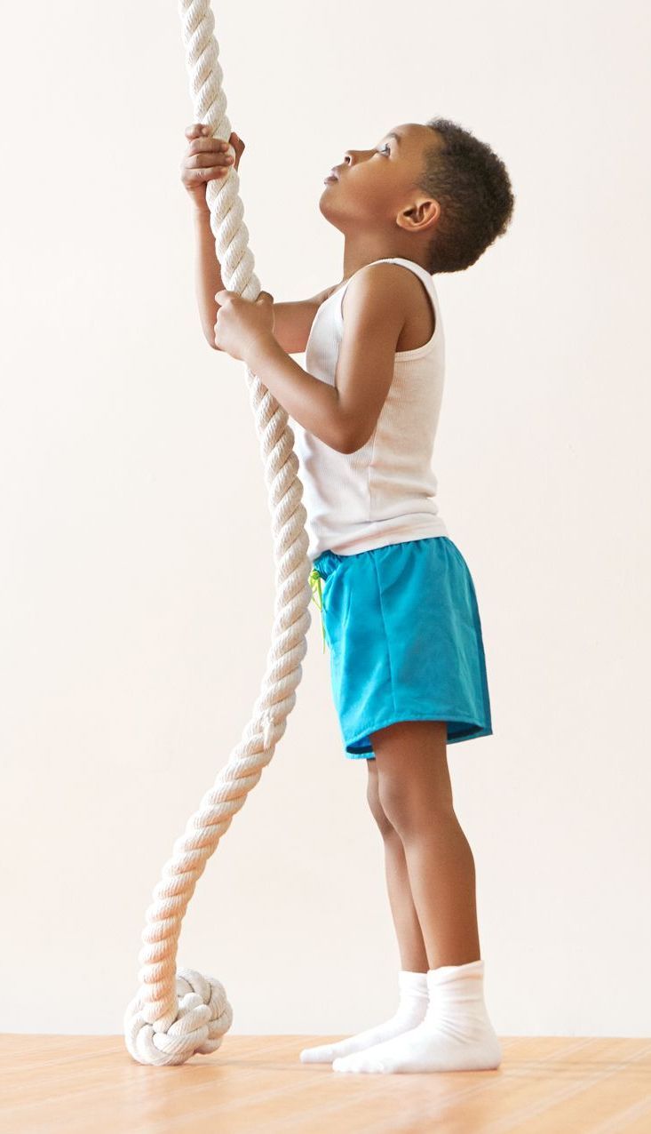 A woman is helping a little boy balance on a balance beam.