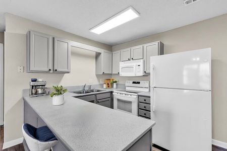 Modern white kitchen with island, appliances, cabinets, and bright overhead lighting