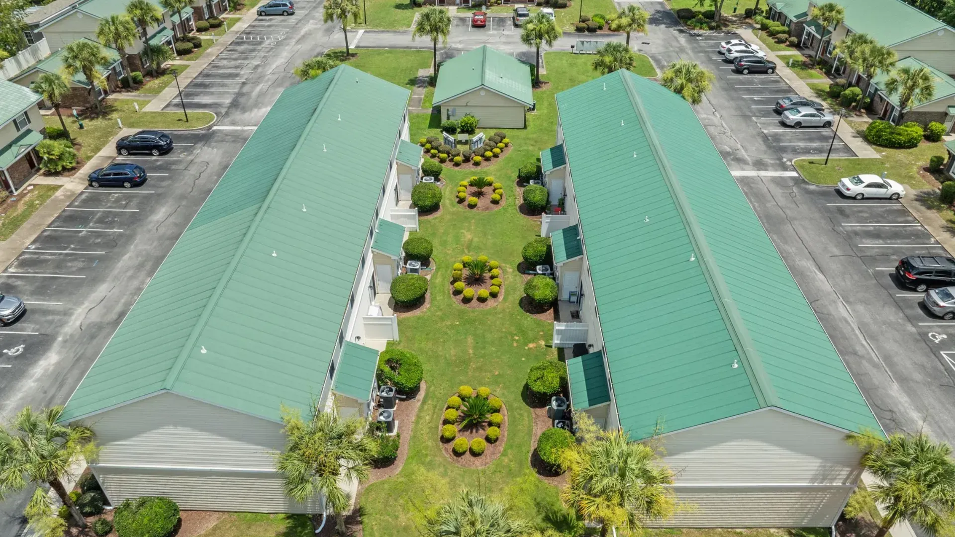 Aerial view of a green-roofed building with a central landscaped courtyard and surrounding parking lots.
