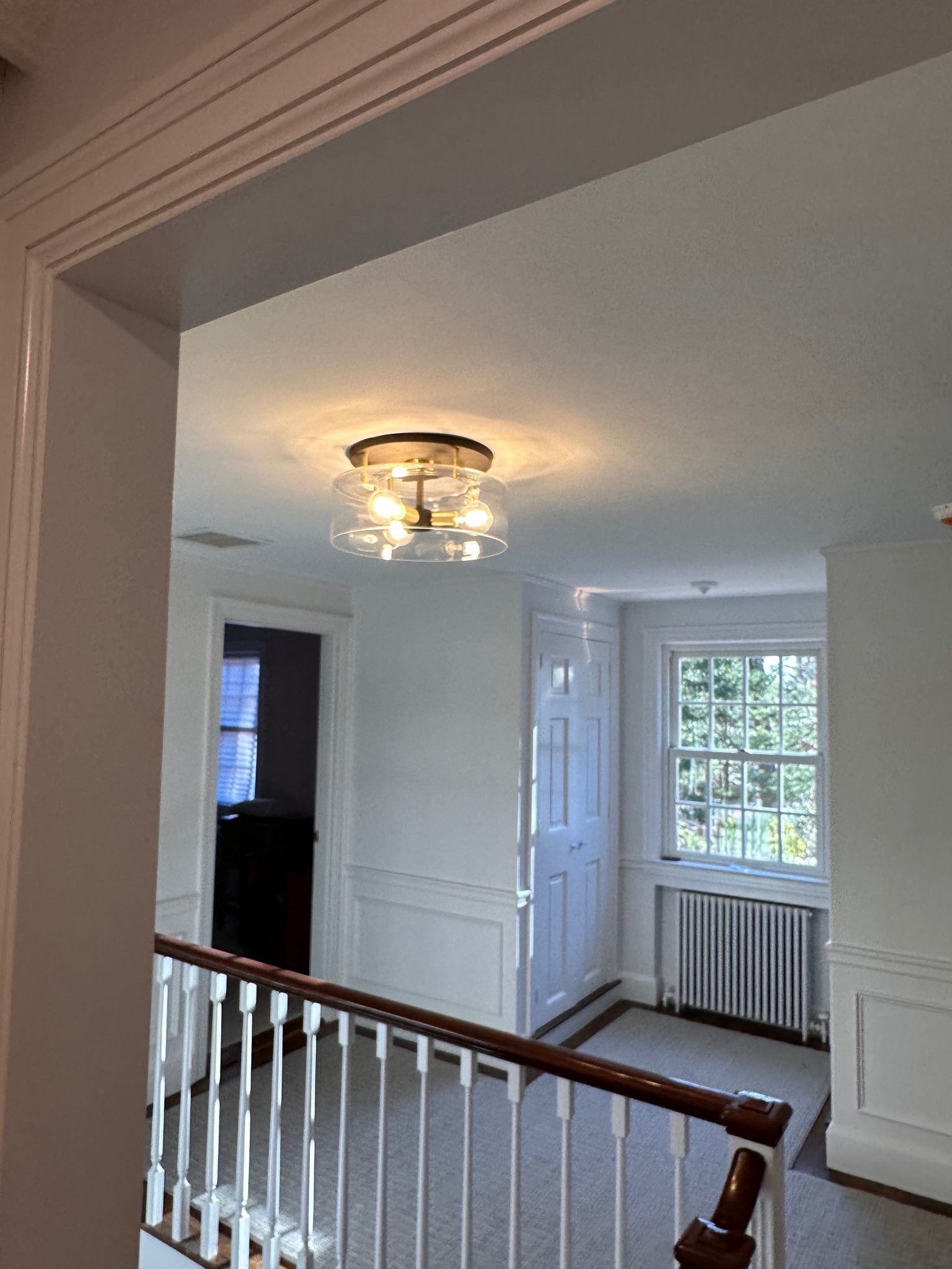 A hallway with a staircase and a window in a house.