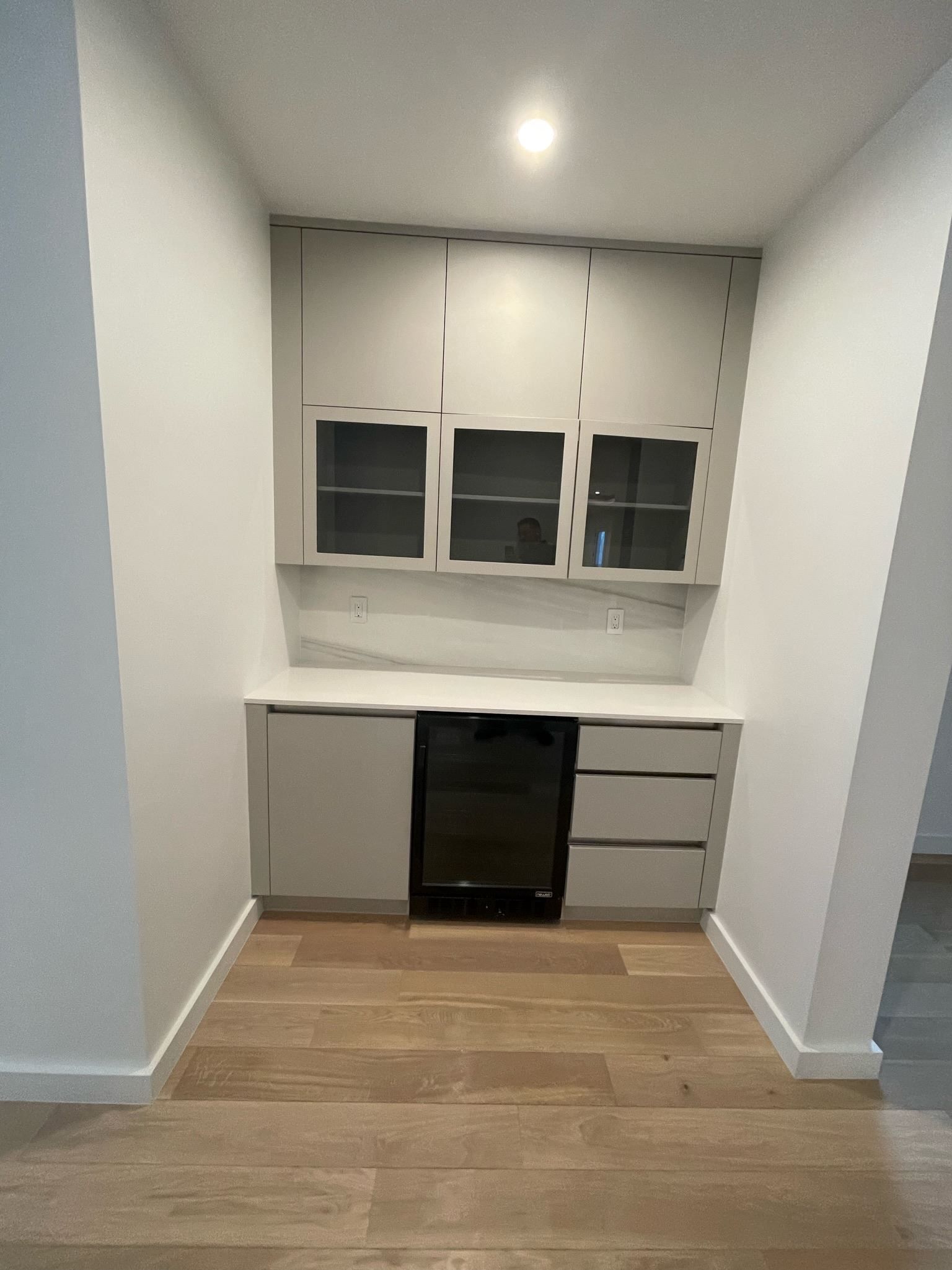 An empty kitchen with white cabinets and wooden floors