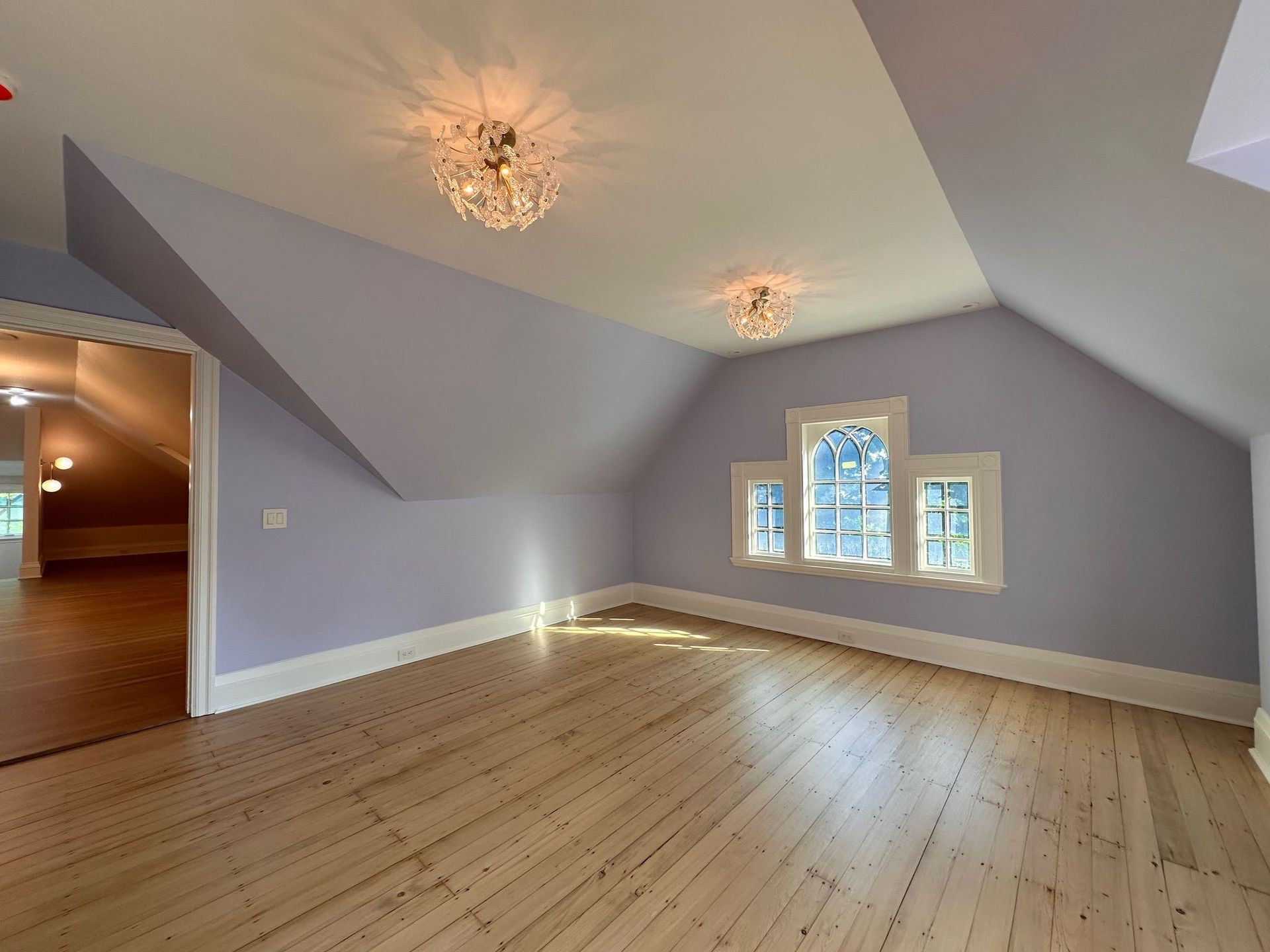 An empty room with purple walls and wooden floors