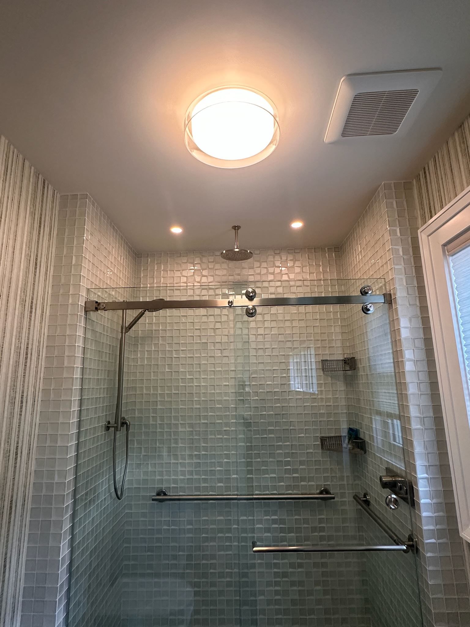 A bathroom with a walk in shower and a light on the ceiling.