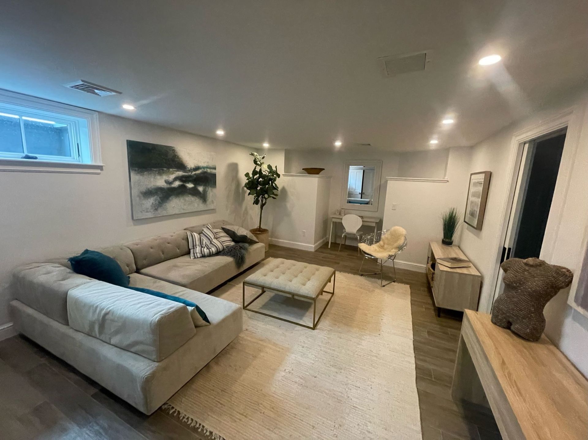 A living room with a couch , coffee table , chair and painting on the wall.