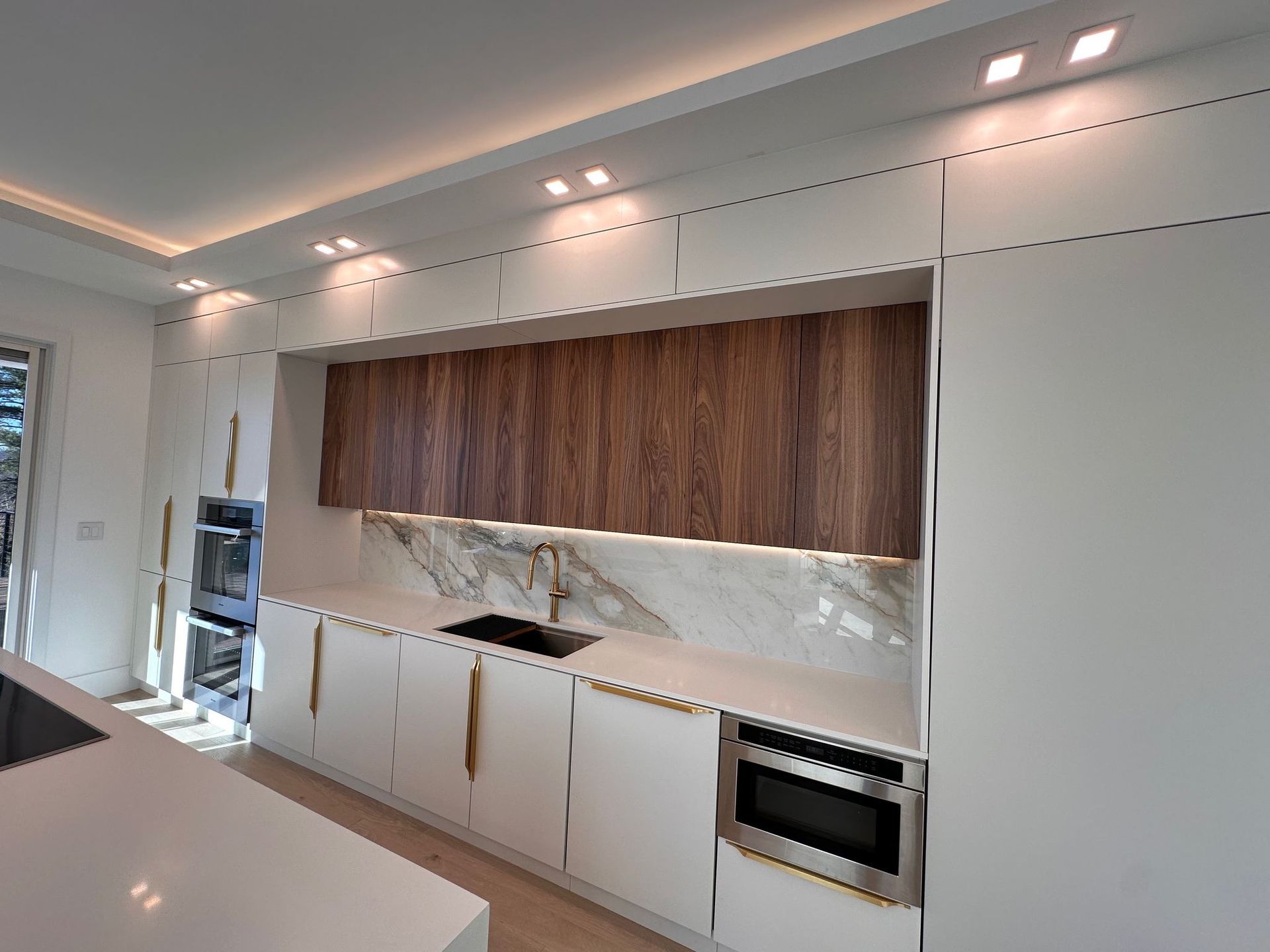 A kitchen with white cabinets and wooden cabinets and a sink.