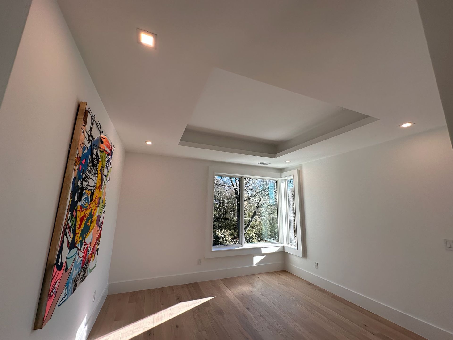 An empty room with a painting on the wall and a window