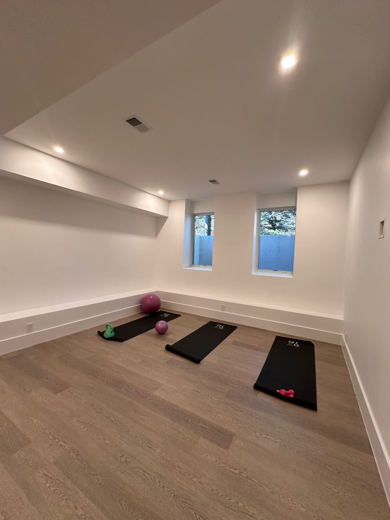 A room with three yoga mats and a ball on the floor.
