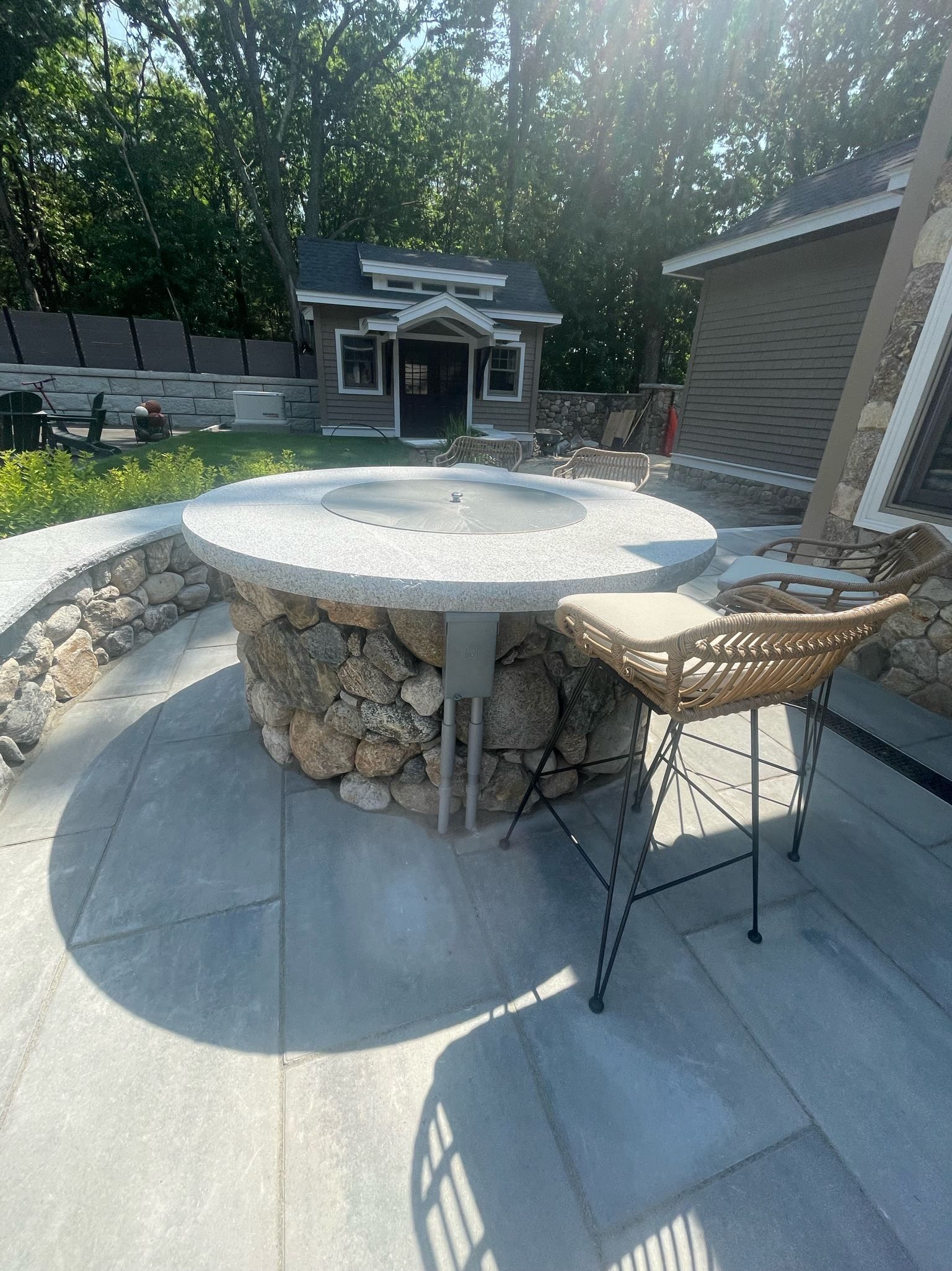 A fire pit with a table and chairs in front of a house.