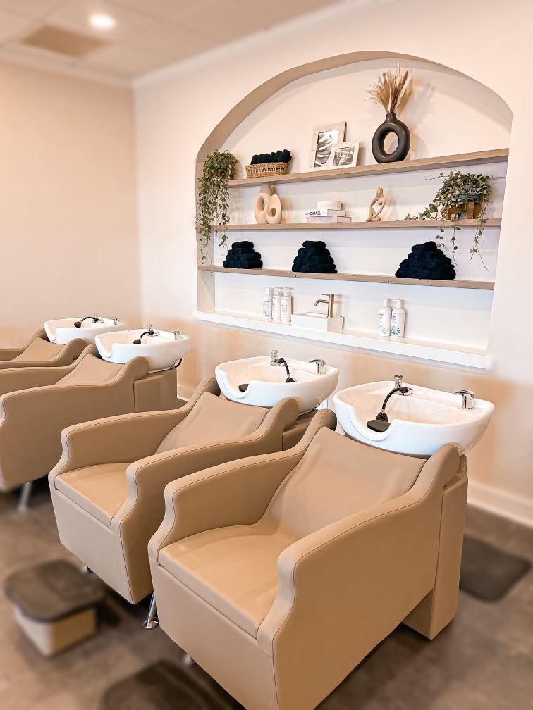 A row of chairs with sinks in a salon.