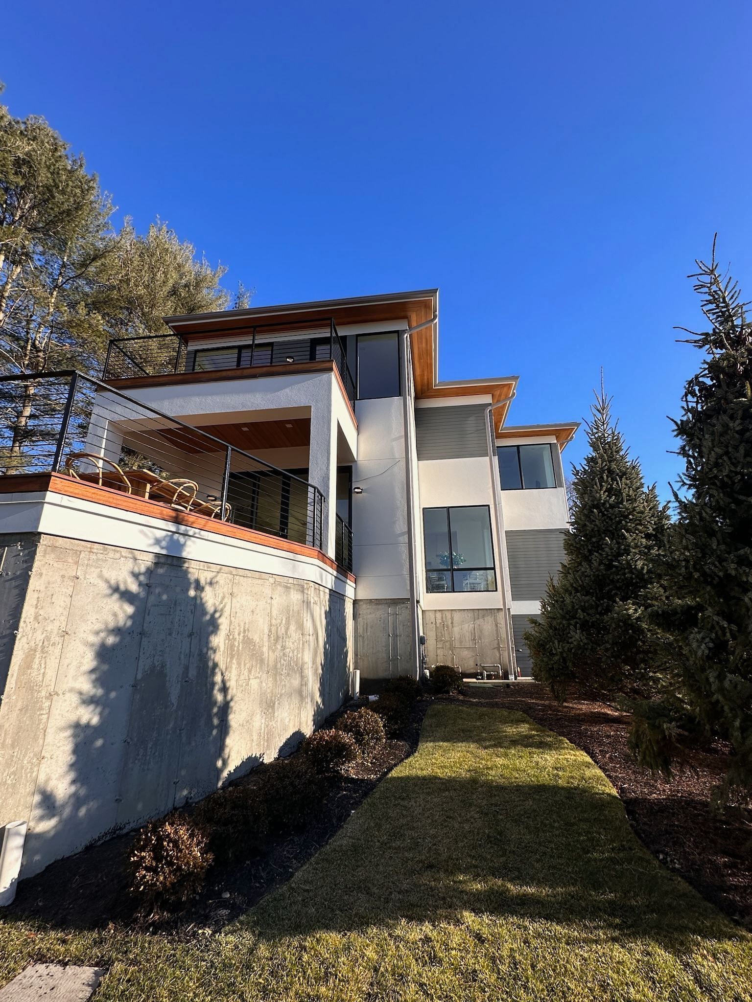 A large white house is sitting on top of a hill surrounded by trees.