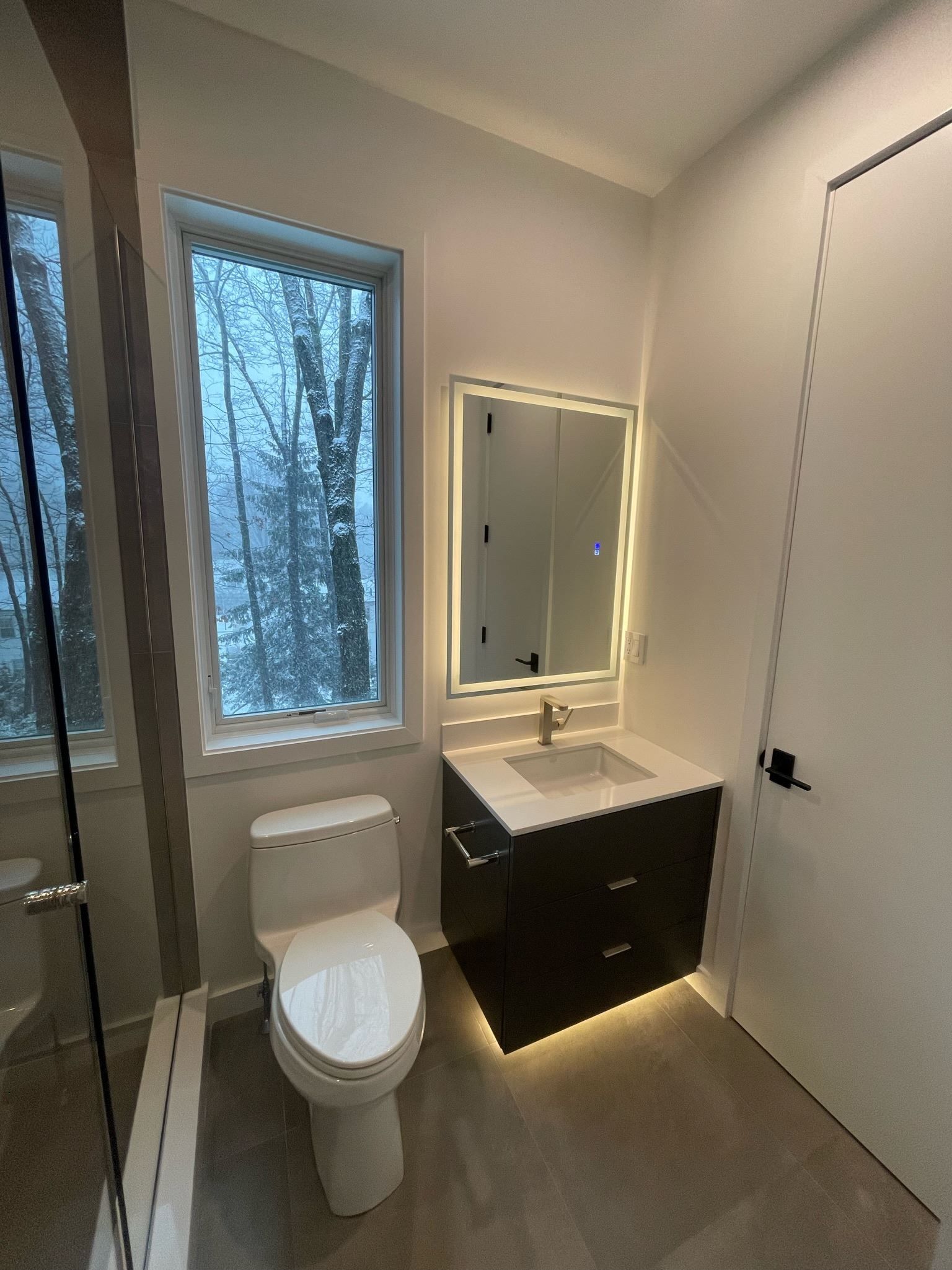 A bathroom with a toilet , sink and mirror