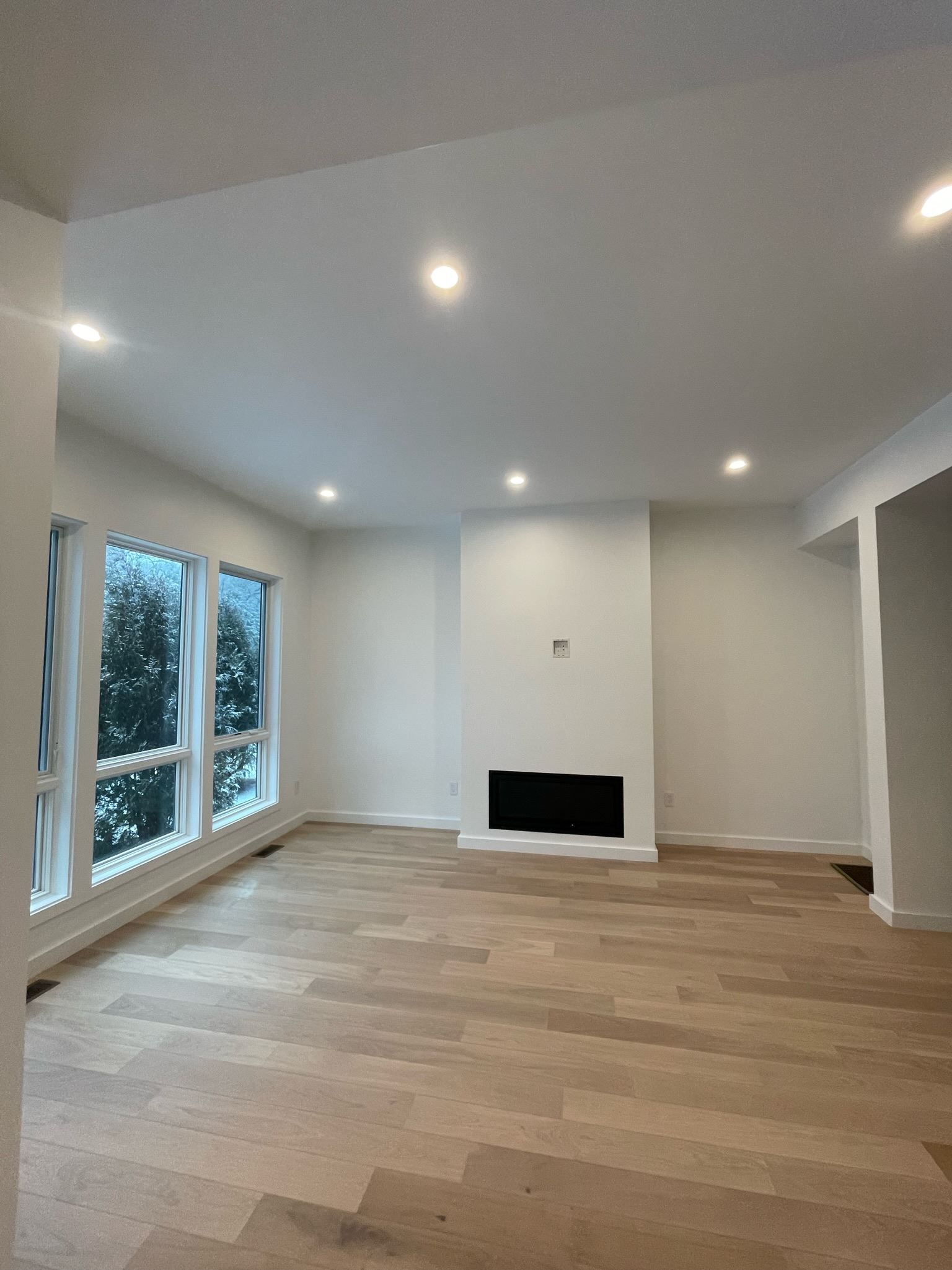 An empty living room with hardwood floors and a fireplace