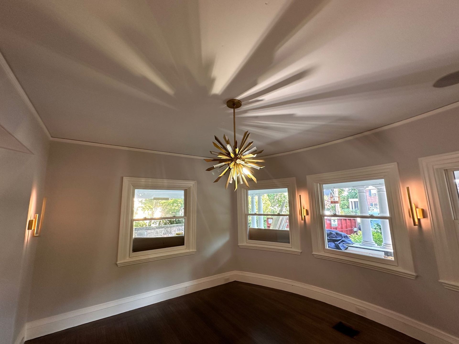 An empty room with a ceiling fan and a chandelier hanging from the ceiling.