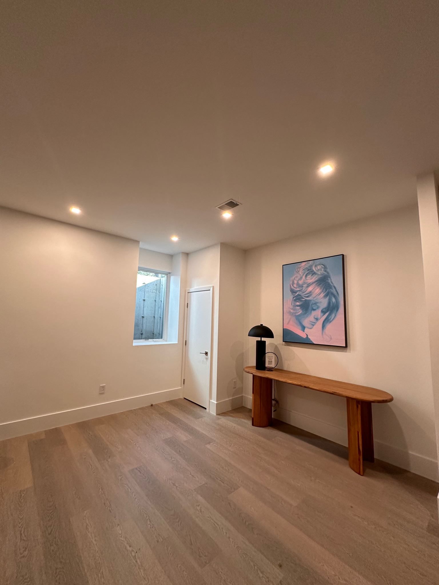An empty room with a wooden table and a painting on the wall.