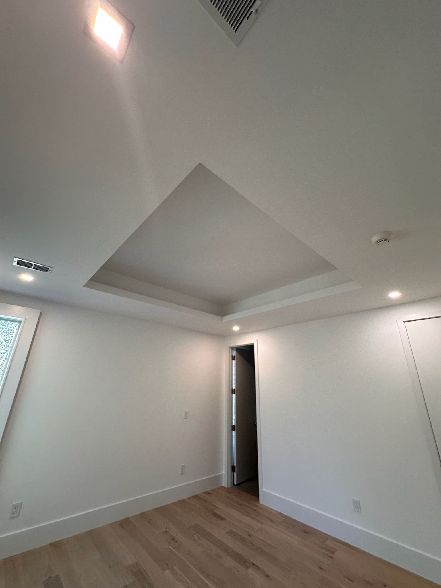 An empty room with hardwood floors and white walls.