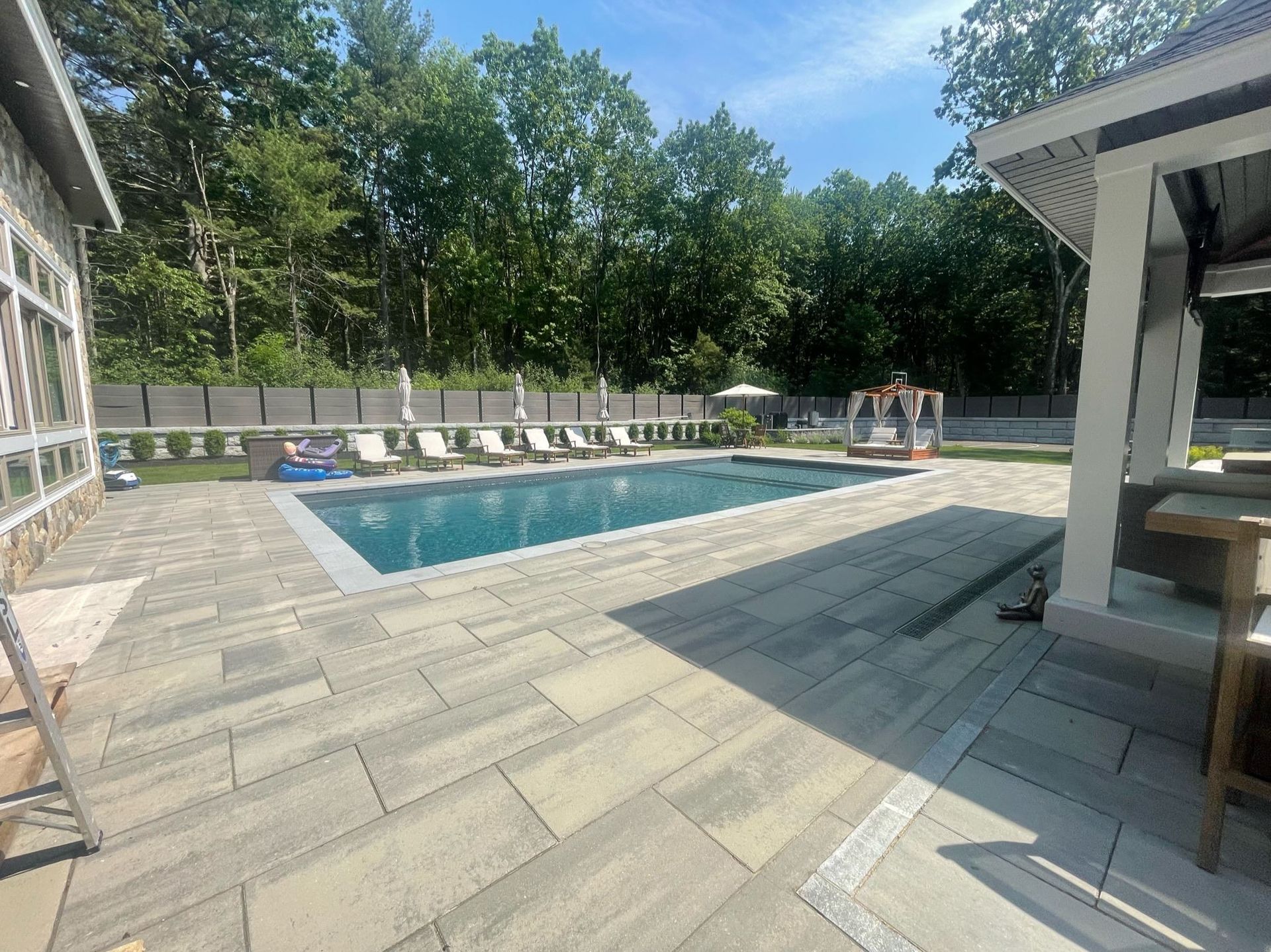 There is a large swimming pool in the backyard of a house.