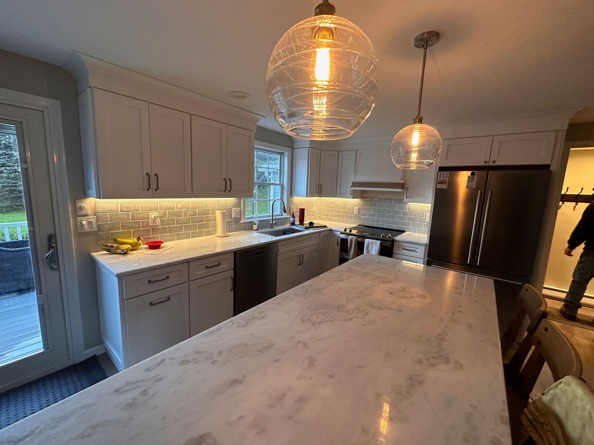 A kitchen with white cabinets and a marble counter top.