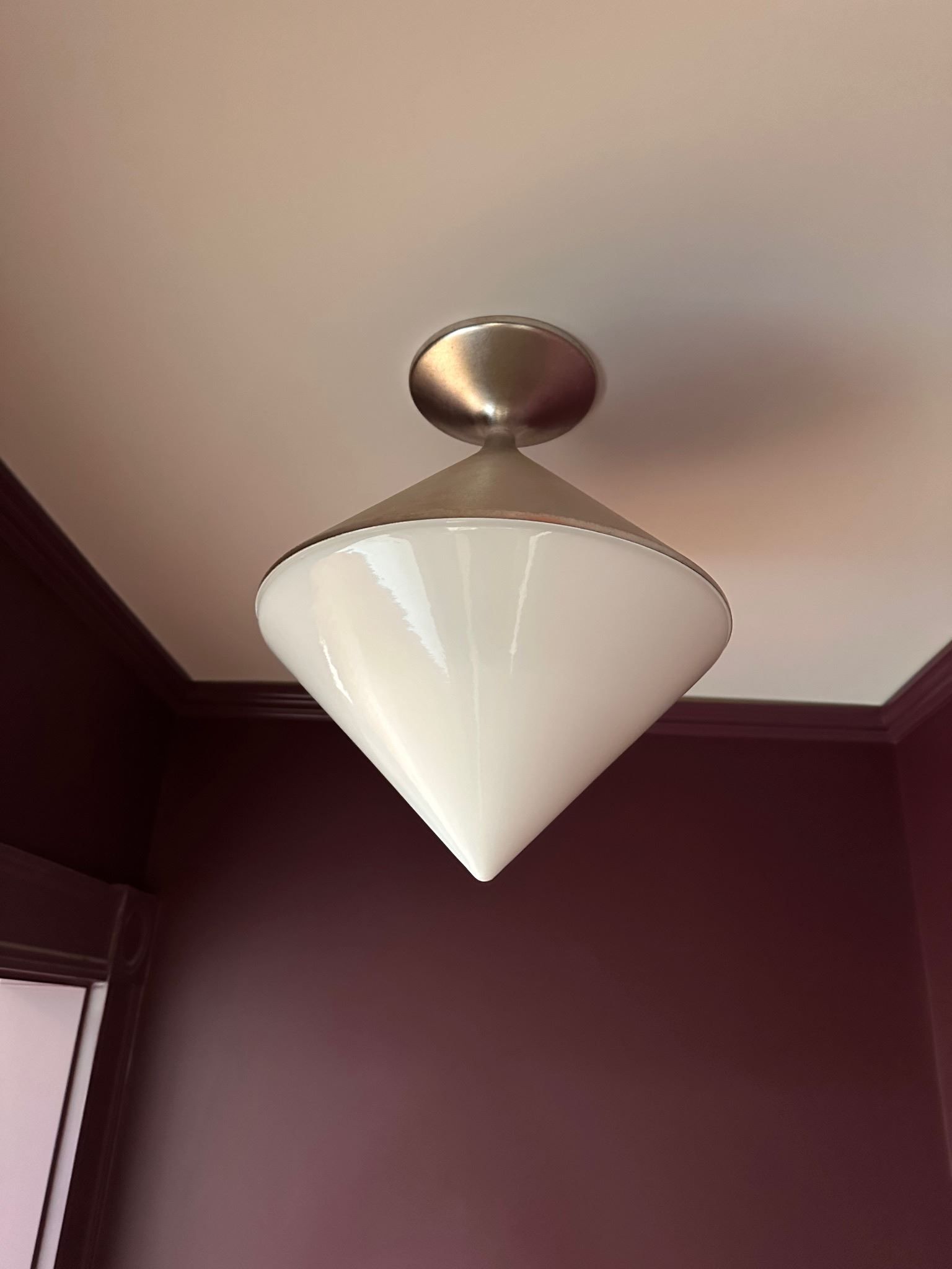 A white cone shaped light fixture is hanging from the ceiling