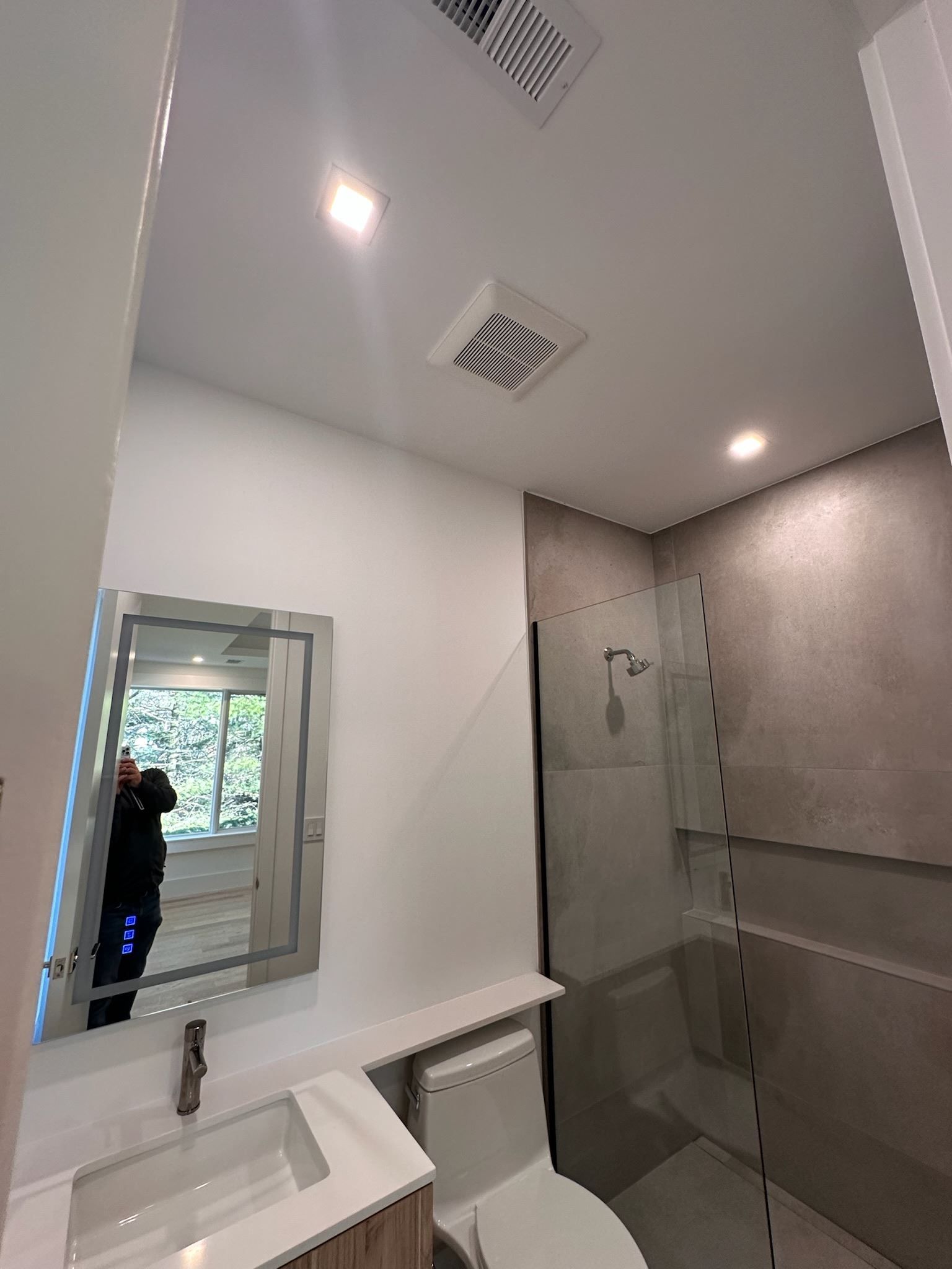 A bathroom with a toilet , sink , mirror and shower.