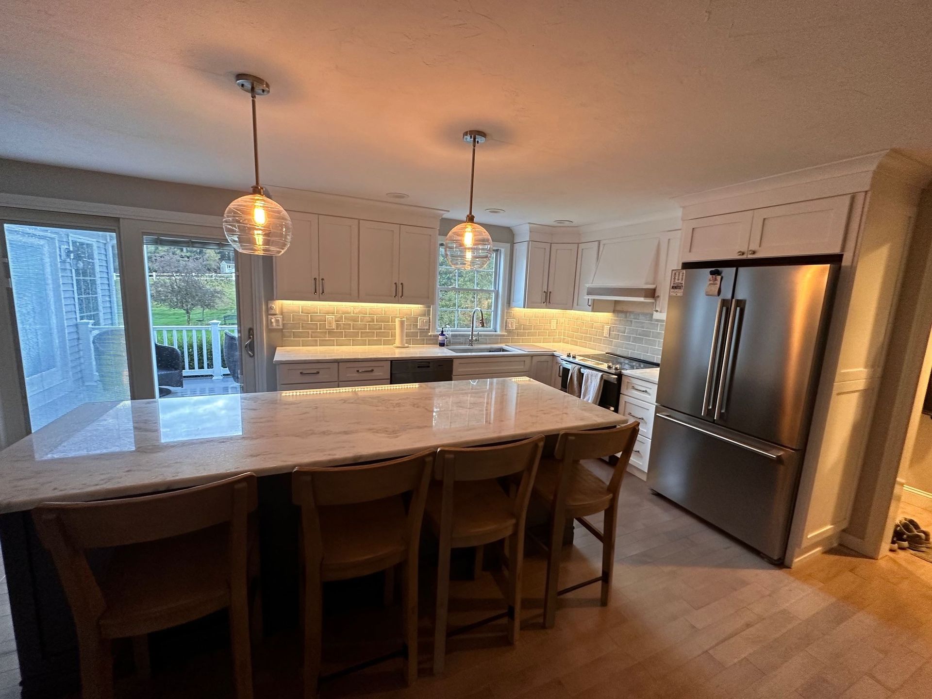 A kitchen with white cabinets , stainless steel appliances , a large island , and a refrigerator.