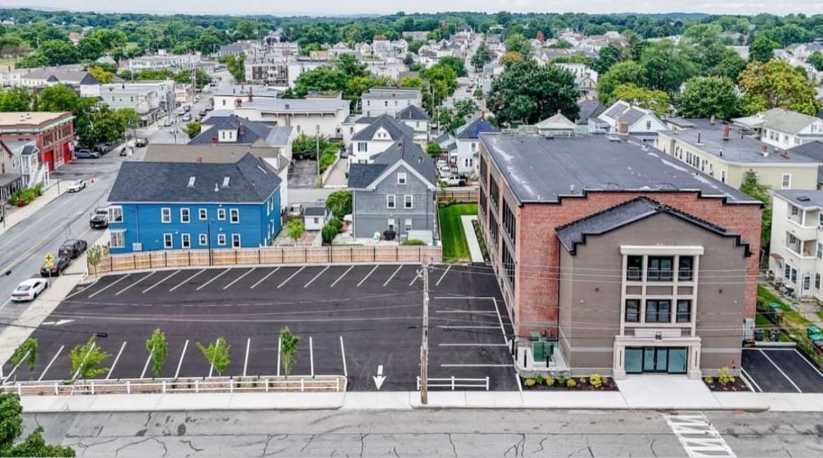 An aerial view of a city with a large parking lot in front of a building.