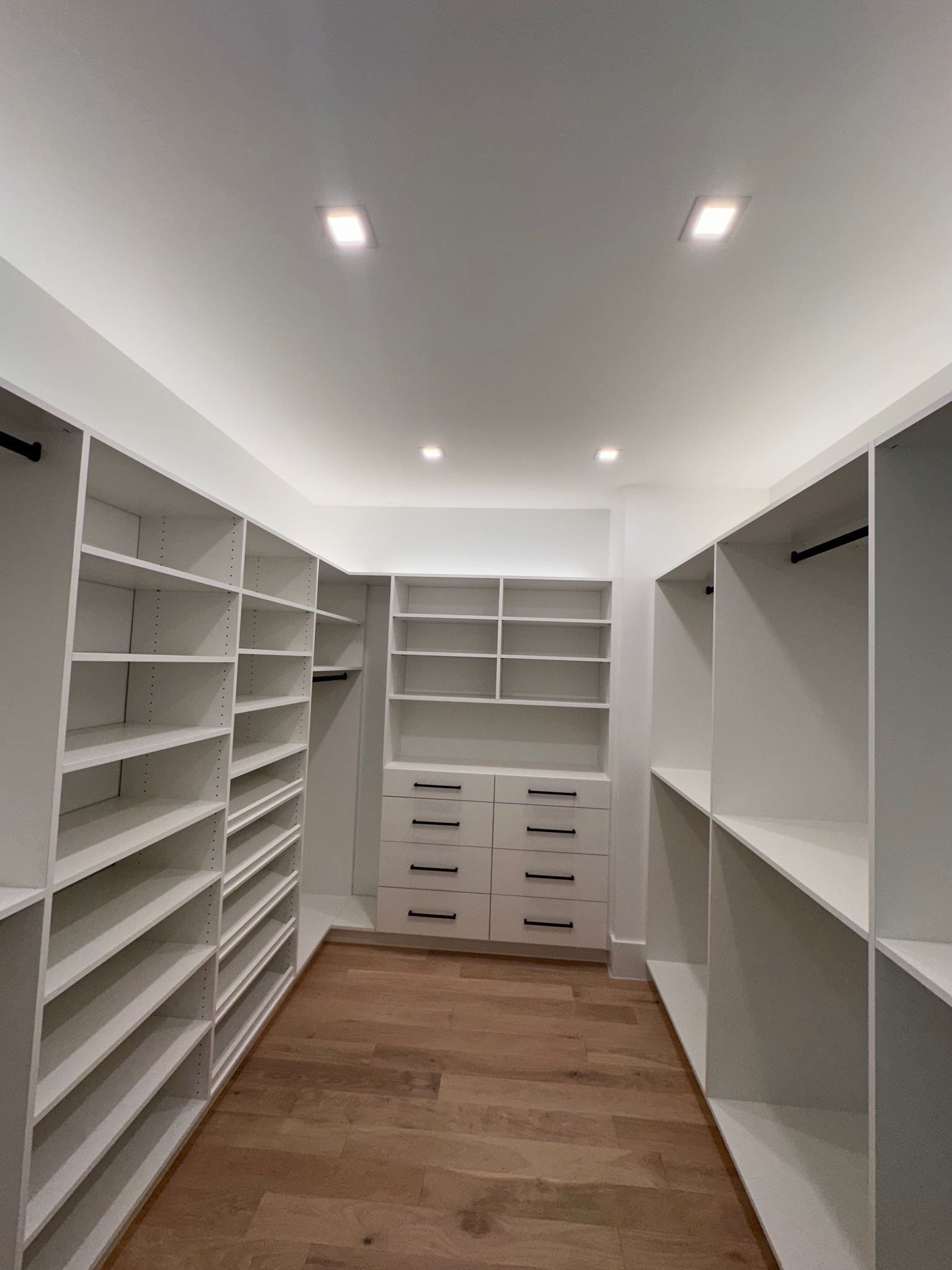 A walk in closet with lots of shelves and drawers.