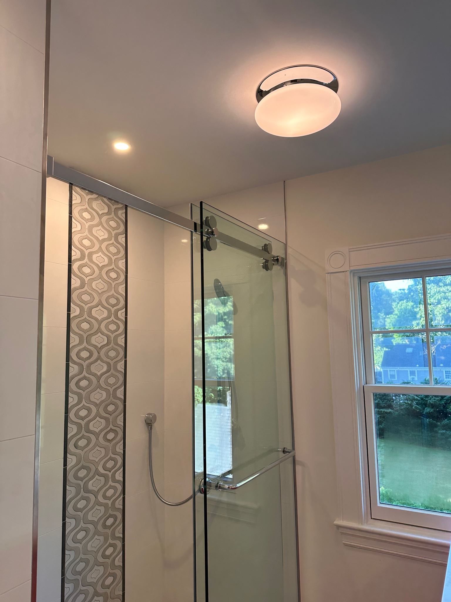 A bathroom with a sliding glass shower door and a window.
